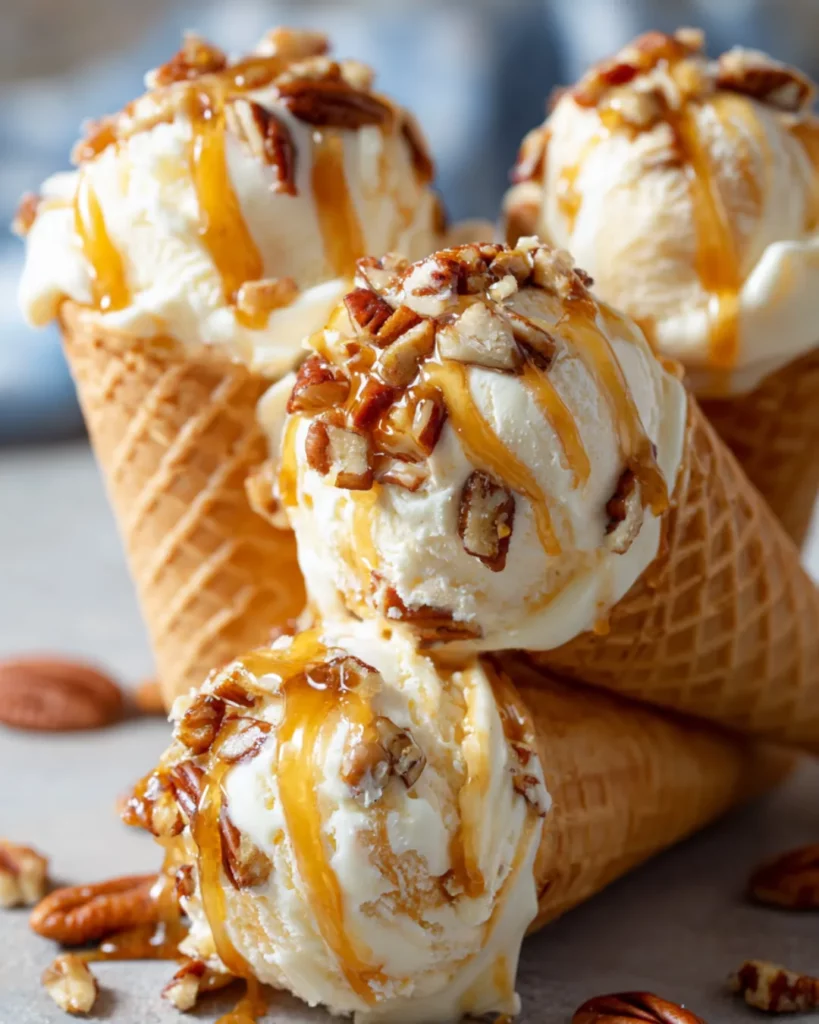 Scoops of pecan ice cream in waffle cones with caramel drizzle and toasted pecans on top
