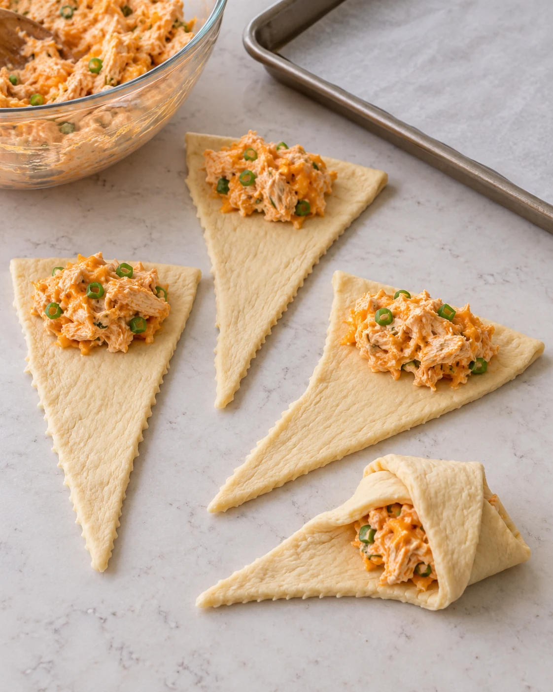 Buffalo chicken filling portioned onto crescent dough triangles