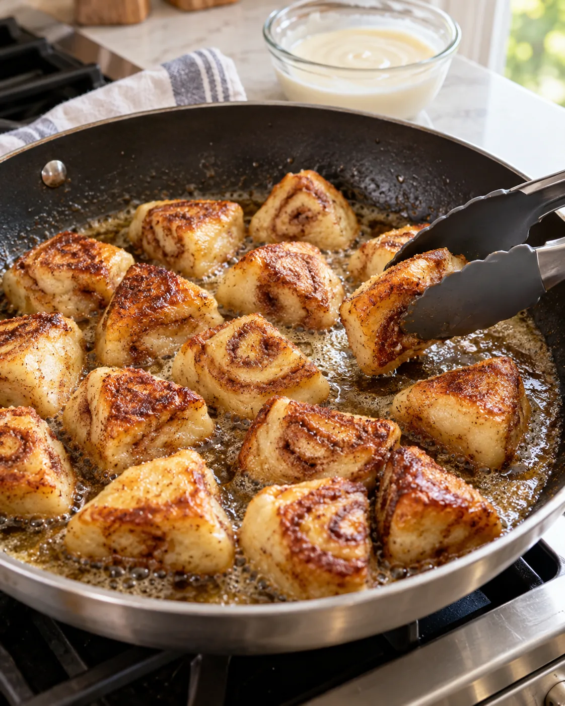 Cinnamon roll French toast bites cooking until golden in a buttered skillet
