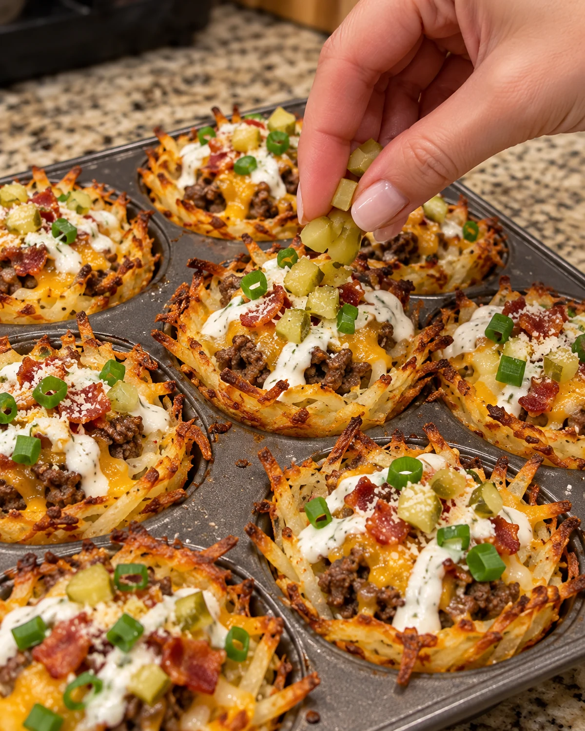 Cheesy hash brown cups topped with chopped dill pickles, ranch, Parmesan, bacon, and green onions