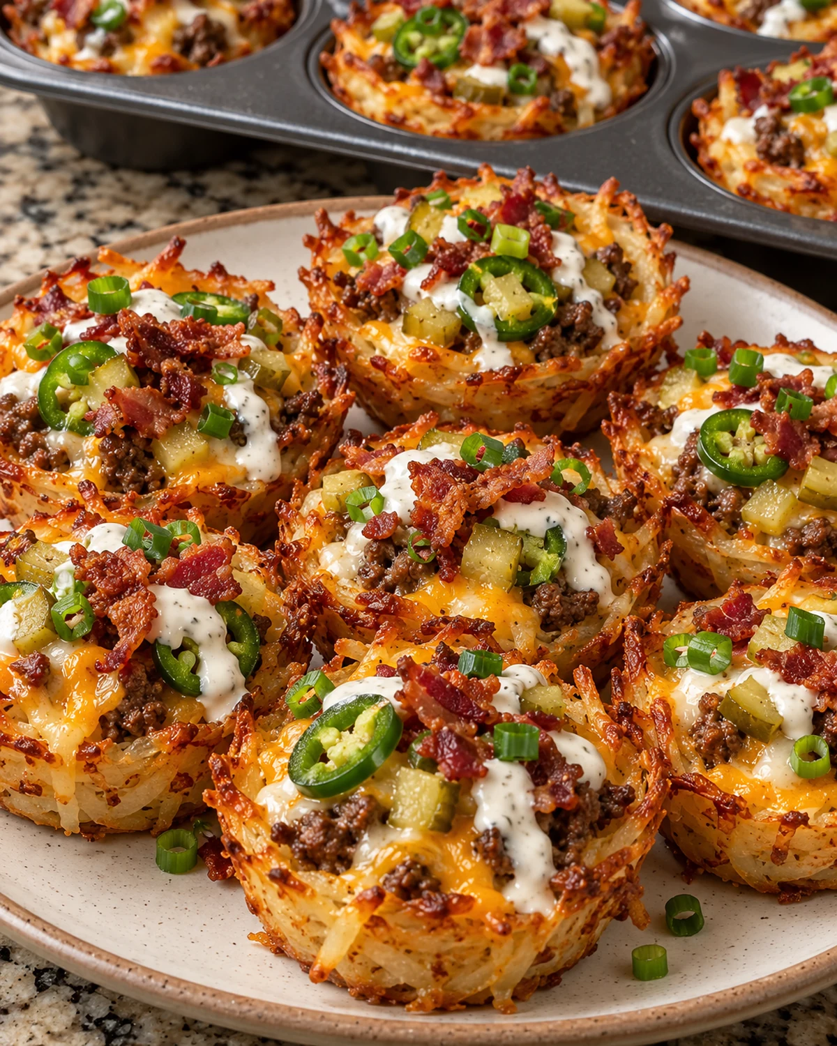 Cheesy hash brown cups topped with jalapeño, pickles, ranch, bacon, and green onions