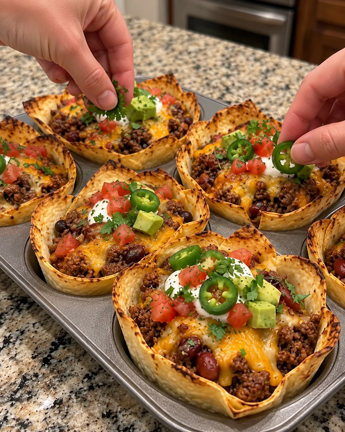 Baked cheesy tortilla cups garnished with sour cream, tomato, avocado, cilantro, and jalapeño